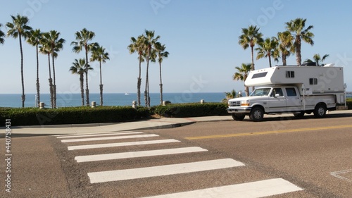 Motorhome trailer or caravan for road trip. Waterfront tropical palm trees and pacific ocean beach, Oceanside California USA. Beachfront vacations in camper van, RV motor home. Mobile home campervan.