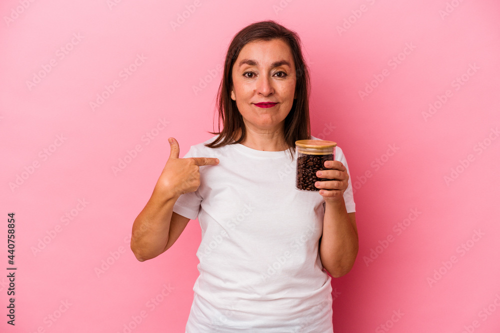 Middle age caucasian woman holding a coffee jar isolated on pink background person pointing by hand to a shirt copy space, proud and confident Middle age caucasian woman holding a coffee jar isolated on pink background person pointing by hand to a shirt copy space, proud and confident
