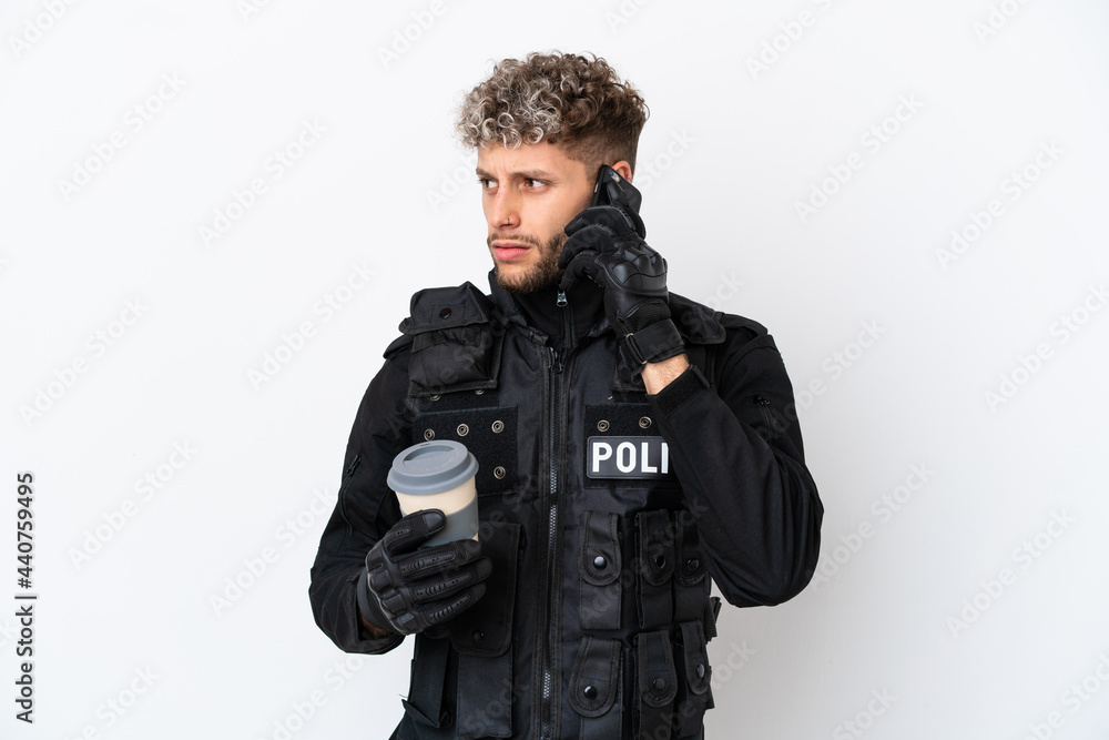 SWAT caucasian man isolated on white background holding coffee to take away and a mobile