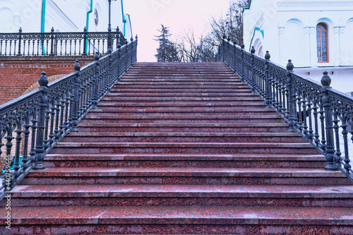 Staircase with granite steps and shaped metal handrails leading up