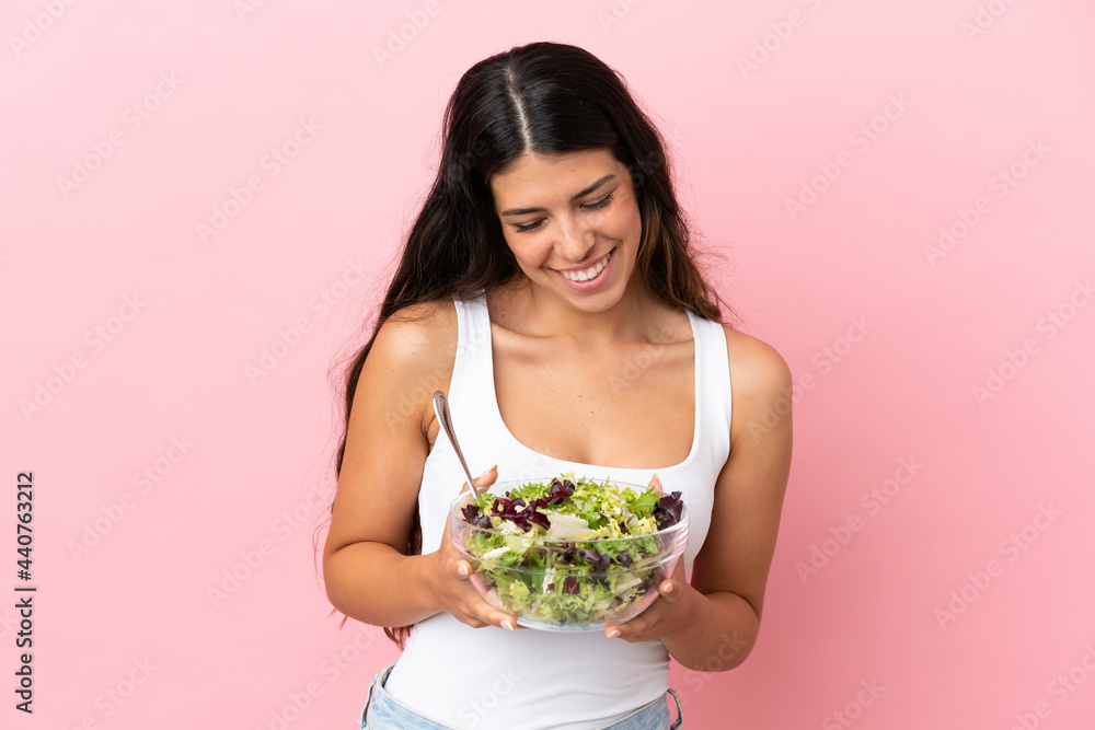 Young caucasian woman isolated on pink background holding a bowl of salad with happy expression Young caucasian woman isolated on pink background holding a bowl of salad with happy expression