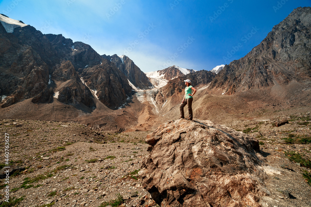 Photo of a tourist girl in the Altai Mountains. In the background is the Bolshoy Aktru Glacier.