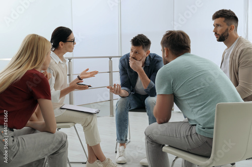 Psychotherapist working with group of drug addicted people at therapy session indoors photo