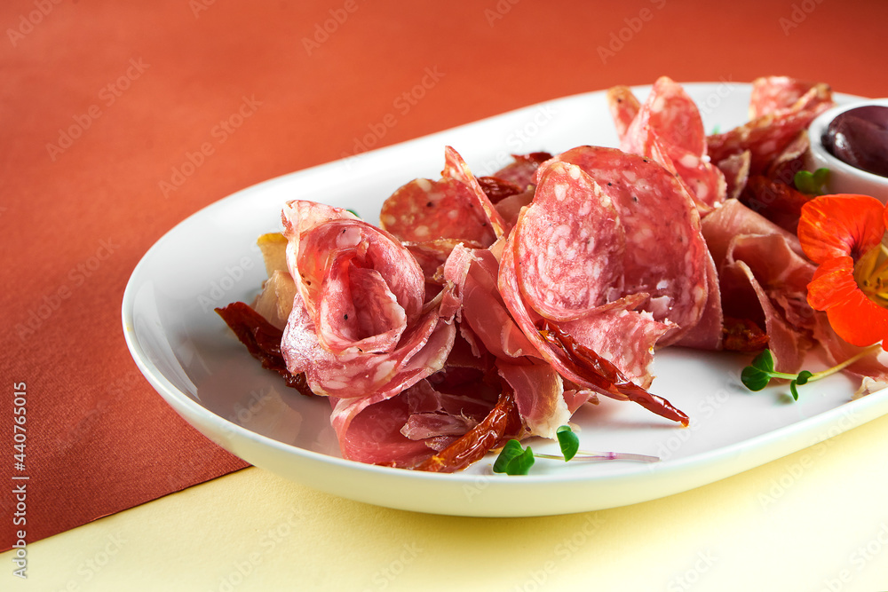 Appetizer - antipasti meat plate with salami, jamon and olives on bright colored backgrounds Appetizer - antipasti meat plate with salami, jamon and olives on bright colored backgrounds
