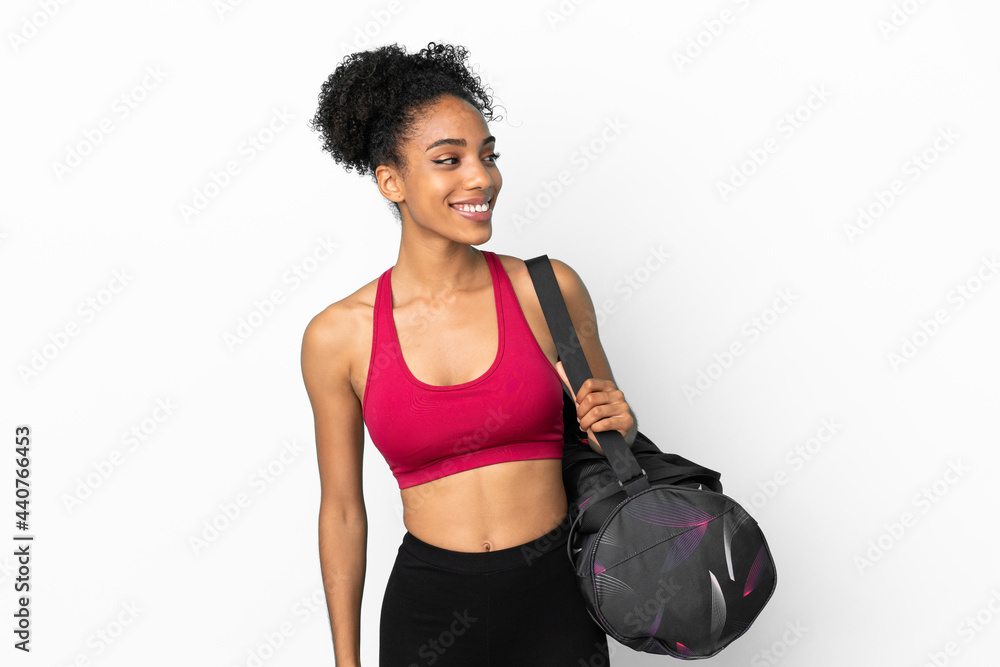 Young sport african american woman with sport bag isolated on blue background looking to the side and smiling