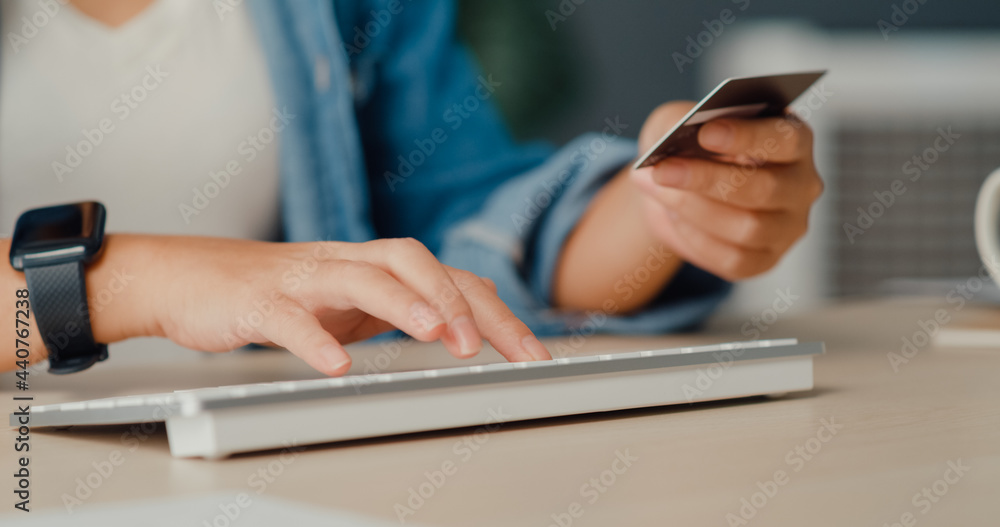 Young asia lady using computer order online shopping product and paying bill with credit card in living room interior. Stay at house, Self quarantine activity, Fun activity for coronavirus prevention. Young asia lady using computer order online shopping product and paying bill with credit card in living room interior. Stay at house, Self quarantine activity, Fun activity for coronavirus prevention.