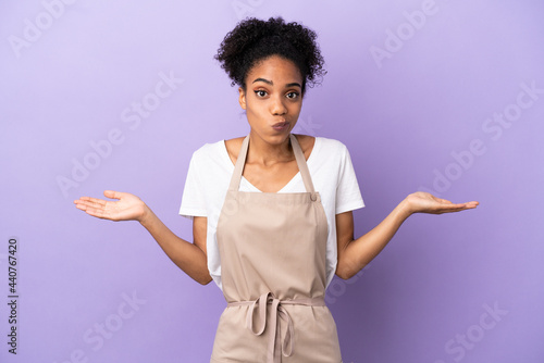 Restaurant waiter latin woman isolated on purple background having doubts while raising hands