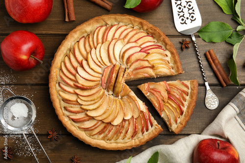 Delicious apple pie and ingredients on wooden table, flat lay