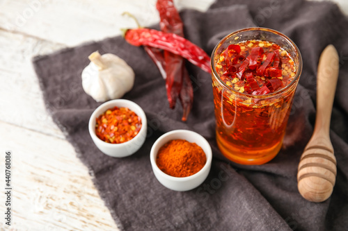 Glass of hot honey and ingredients on light wooden background photo