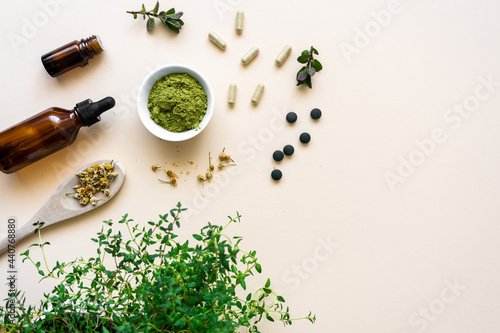 Grünes Kräuter Pulver in einer Schüssel, Medikamenten Kapseln und Tabletten auf einem beigen Hintergrund. Kräuter Medizin.