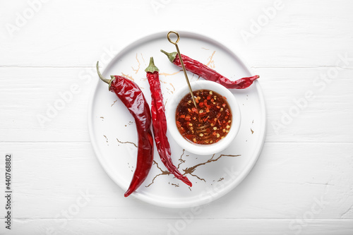 Fototapeta Naklejka Na Ścianę i Meble -  Tray with hot honey and dry chili peppers on light wooden background