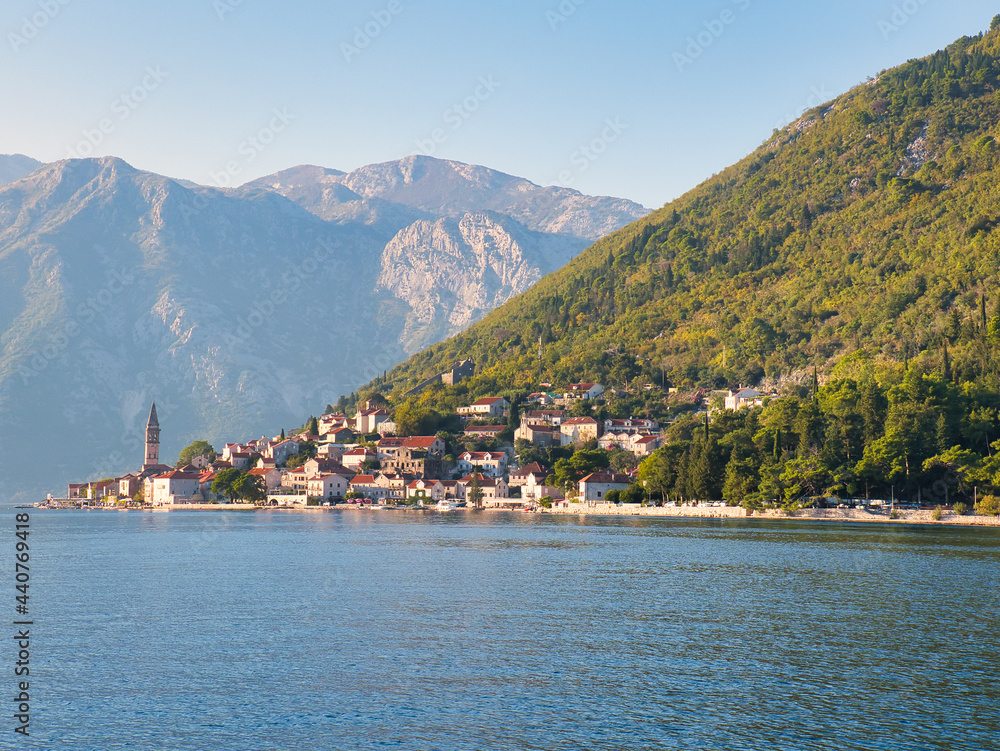 View of the old town of Perast with the church tower and mountains, seen from the Bay of Kotor, on a sunny autumn day