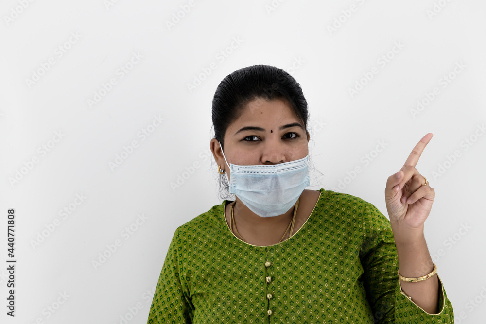 Beautiful smiling Indian young woman in protective face mask not wearing properly and saying wear proper, healthcare concept, isolated over white background Beautiful smiling Indian young woman in protective face mask not wearing properly and saying wear proper, healthcare concept, isolated over white background