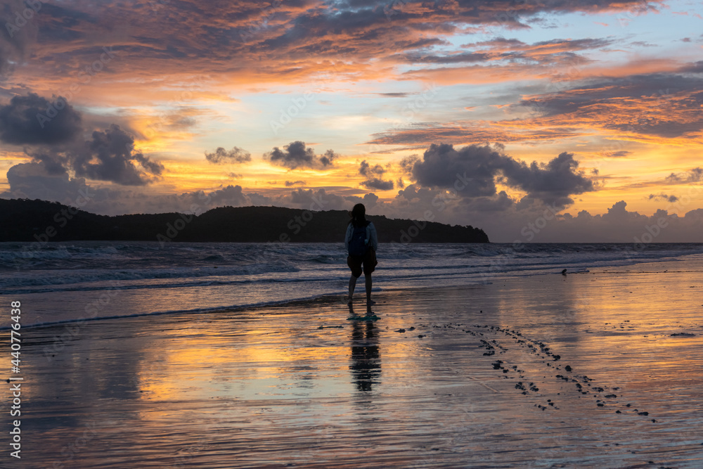 Girl walking on beach at sunset