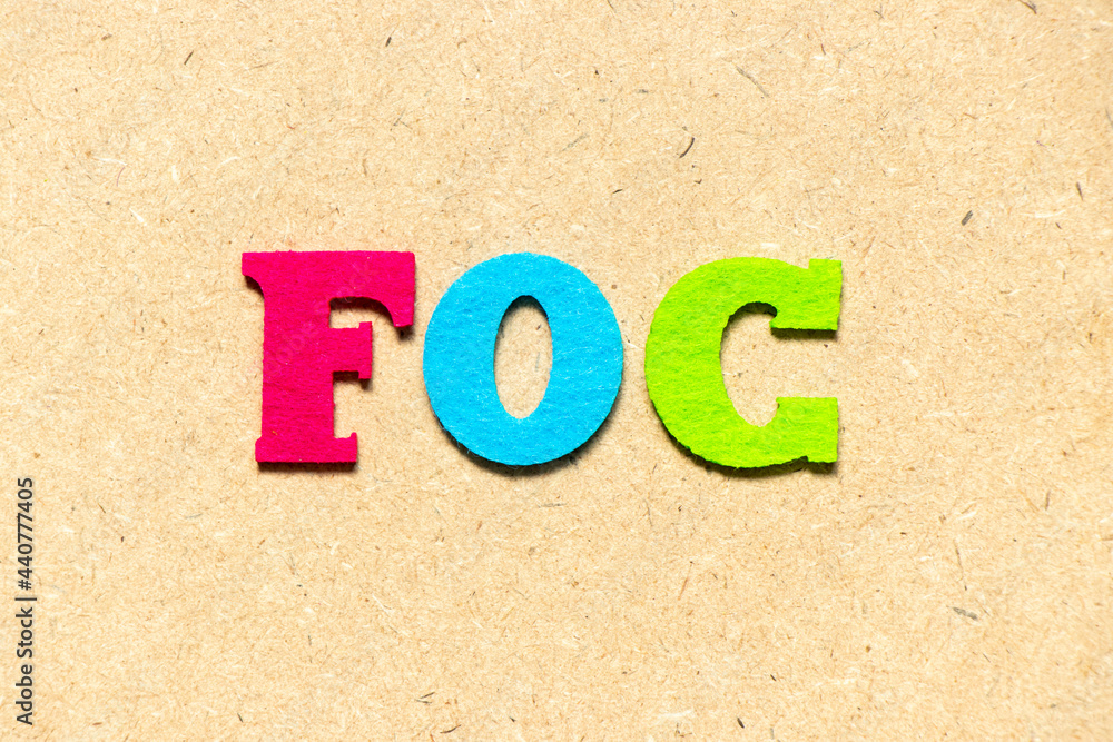 Color cloth alphabet letter in word FOC (Abbreviation of Free of charge) on wood background