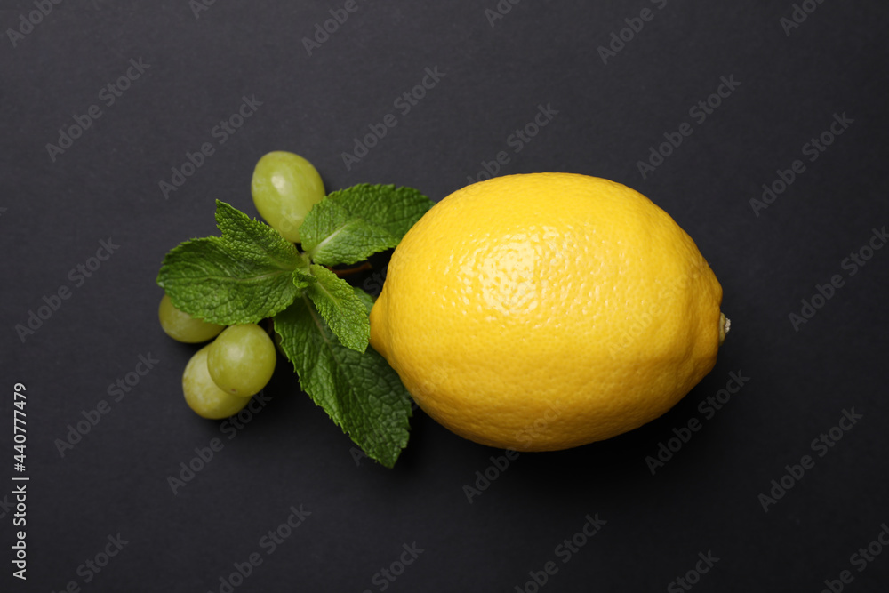 Fresh ripe lemon, grapes and mint on black background, flat lay