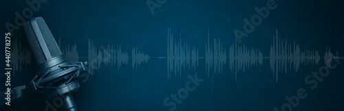 Podcast banner background with studio microphone and waveform on dark blue concrete background. Podcasting header design with copy space