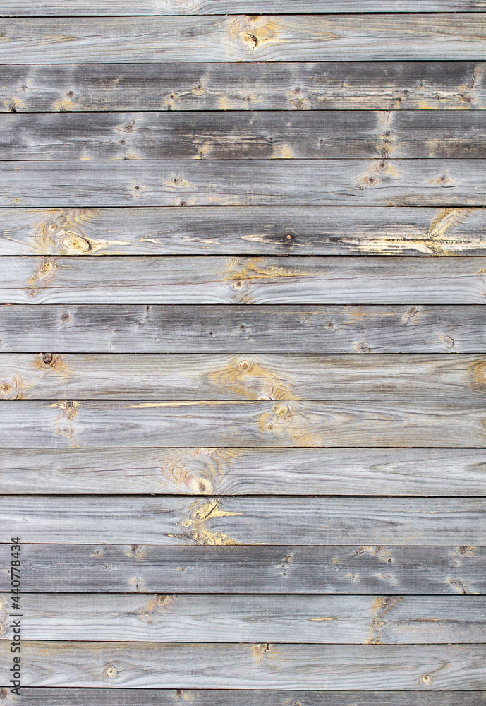 Fototapeta premium Wooden background made of old boards. The texture of an old rustic wooden fence made of flat processed boards. Wooden fence made of old boards with the inclusion of Knots. Background design