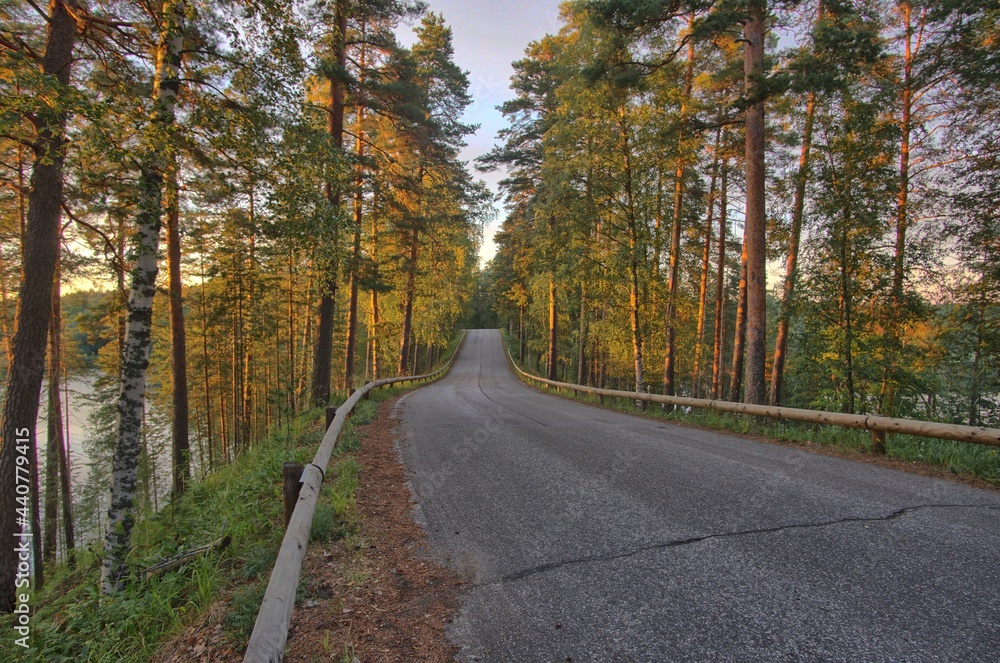 Obraz premium Summer road between lakes at sunset