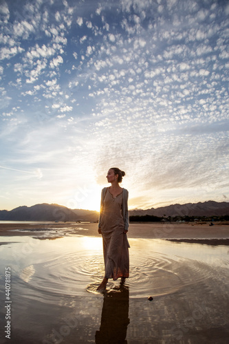 Beautiful woman dancing by the sea at sunset