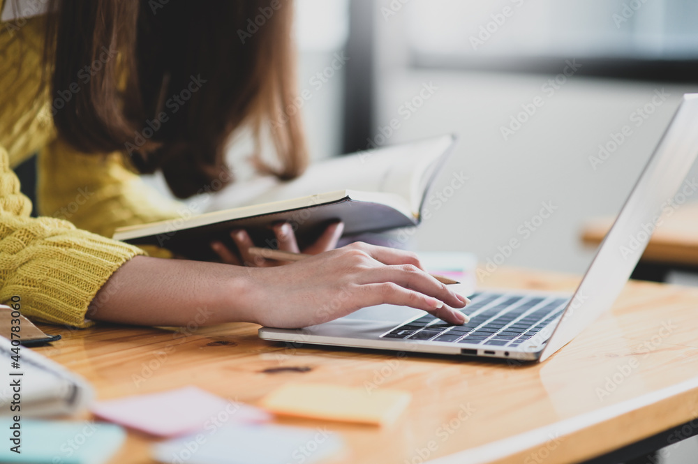 Girl using laptop and holding a book in hand ,She searched for information to learn, Online learning. Girl using laptop and holding a book in hand ,She searched for information to learn, Online learning.