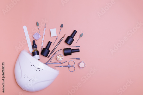 Manicure lamp and tools for applying varnish top view on a colored background. Salon manicure concept photo