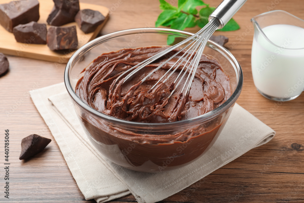 Whipping chocolate cream with balloon whisk on wooden table, closeup Whipping chocolate cream with balloon whisk on wooden table, closeup