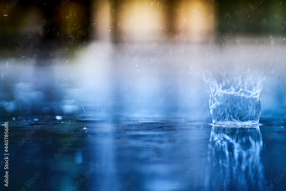 small splashing crown from rain's droplet when fall down on the floor in rainy day with blue shade color tone and golden sun light behind small splashing crown from rain's droplet when fall down on the floor in rainy day with blue shade color tone and golden sun light behind