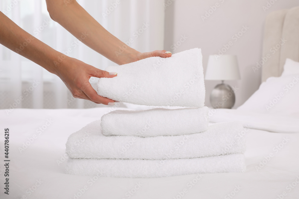 Chambermaid putting fresh towels on bed in hotel room, closeup Chambermaid putting fresh towels on bed in hotel room, closeup