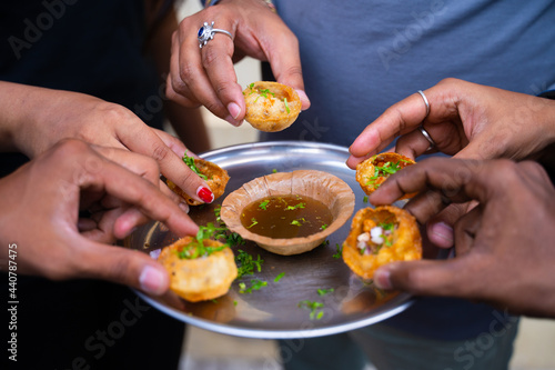 Close up, group of friends Hands taking pani puri Snacks from the plate - Concept of Sharing food or Indian evening street food.