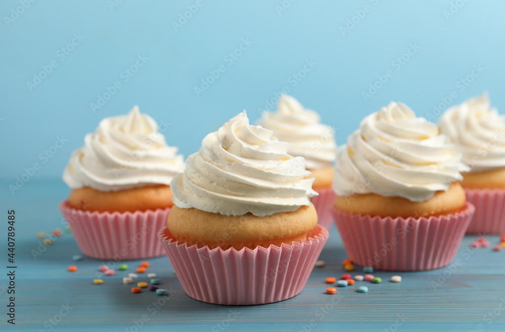 Delicious cupcakes decorated with cream on light blue wooden table