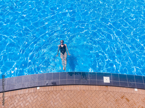 Beautiful woman in pool in hotel. Summer holidays  enjoying summer vacations during quarantine. Aerial drone view