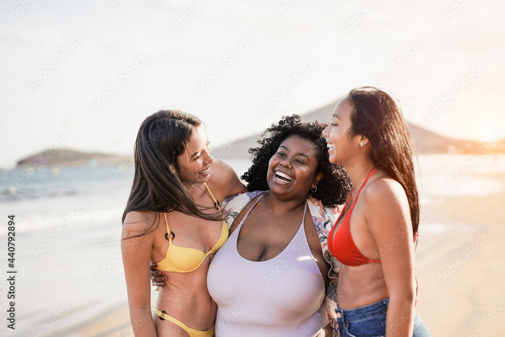Multiracial young women enjoy summer vacation together on the beach - Happy girls with different body and skin colors having fun outdoor Multiracial young women enjoy summer vacation together on the beach - Happy girls with different body and skin colors having fun outdoor