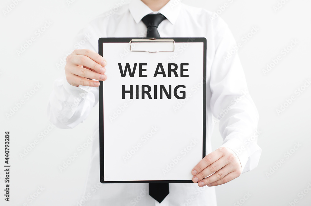 businessman holding a card with text WE ARE HIRING on a light background businessman holding a card with text WE ARE HIRING on a light background