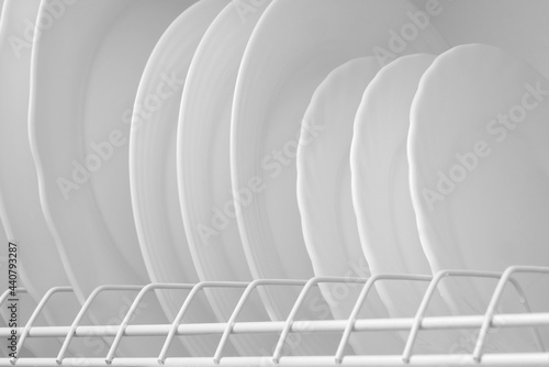 Clean white plates on dish drainer drying after washing