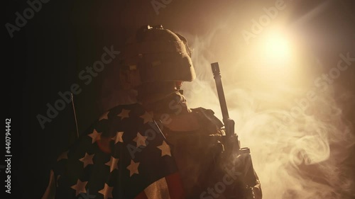 soldier standing with his back to us in the dark holding USA national flag
