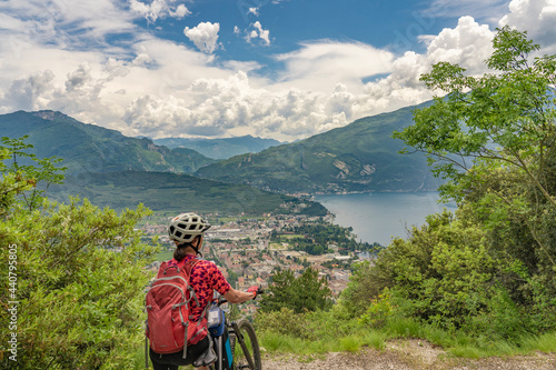 nice senior woman with elctric mountain bike resting and enjoying the awesome view over Garda Lake between Riva del Garda and Torbole 