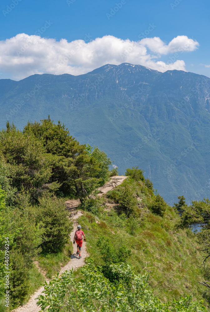 Naklejka premium nice and active senior woman riding her electric mountainbike on the famous Tremalzo downhill from Tremalzo Pass to Riva del Garda at Garda lake, Trentino, Izaly