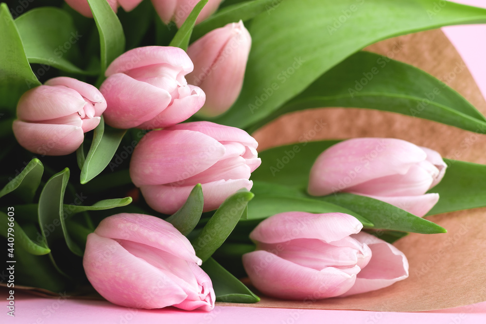 Beautiful delicate bouquet of tulip flowers in craft wrapping paper on pink background Beautiful delicate bouquet of tulip flowers in craft wrapping paper on pink background
