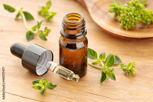 Oregano essential oil and fresh oregano on wooden table. Origanum vulgare oil photo