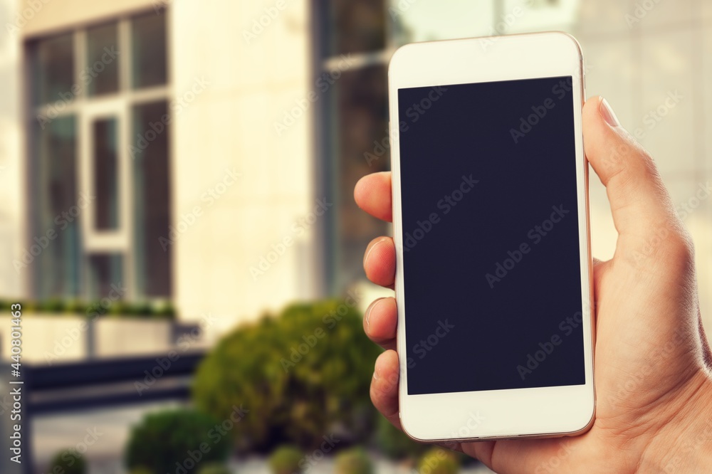 Hand holding mobile phone with blank screen on outdoor background. Hand holding mobile phone with blank screen on outdoor background.