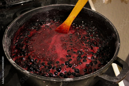 Chokeberry berries are cooked for jam. Cooking chokeberry jam. Chokeberry berries. Aronia. In a sherpa with a spoon. photo