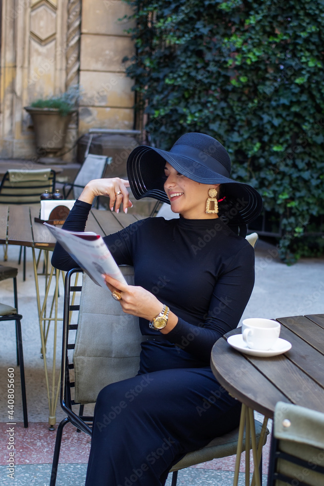 Exquisite woman in a black hat drinks coffee Exquisite woman in a black hat drinks coffee