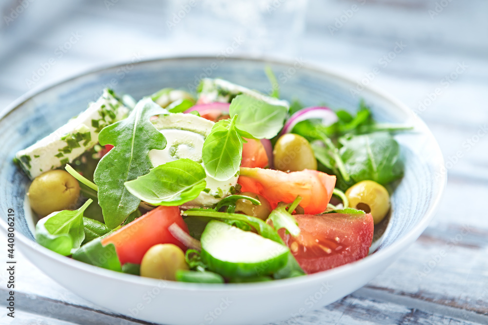 Summer Salad with Cream Cheese, green Olives, Tomatoes and fresh Basil. Bright wooden background. Close up. 