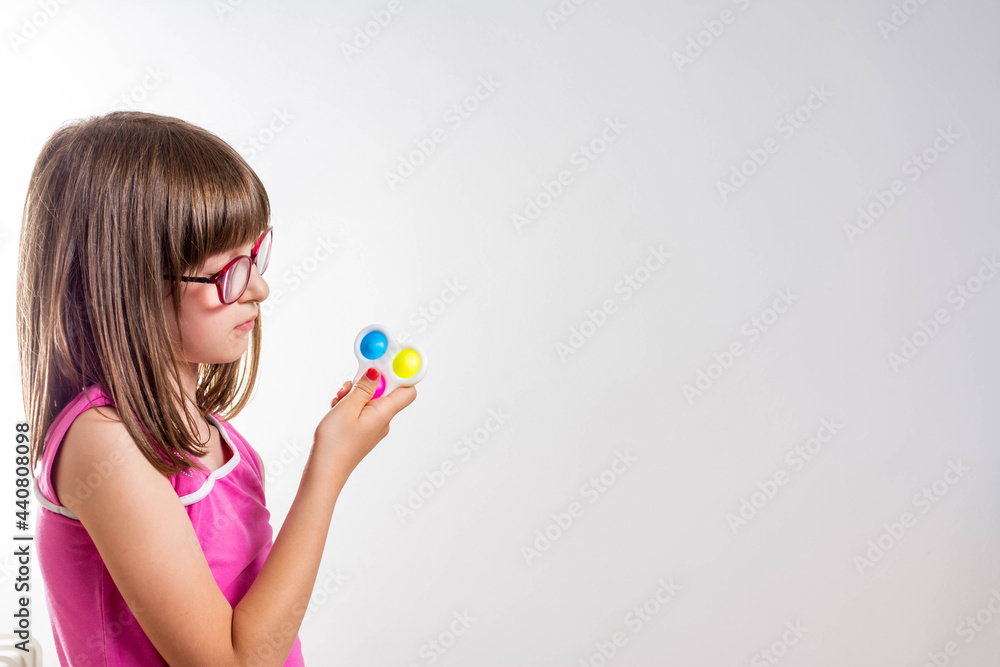 Portrait little girl with a modern popit toy. Colorful and bright pop it toy. Simple dimple. The child is with colorful trendy antistress sensory toy pop it. Portrait little girl with a modern popit toy. Colorful and bright pop it toy. Simple dimple. The child is with colorful trendy antistress sensory toy pop it.