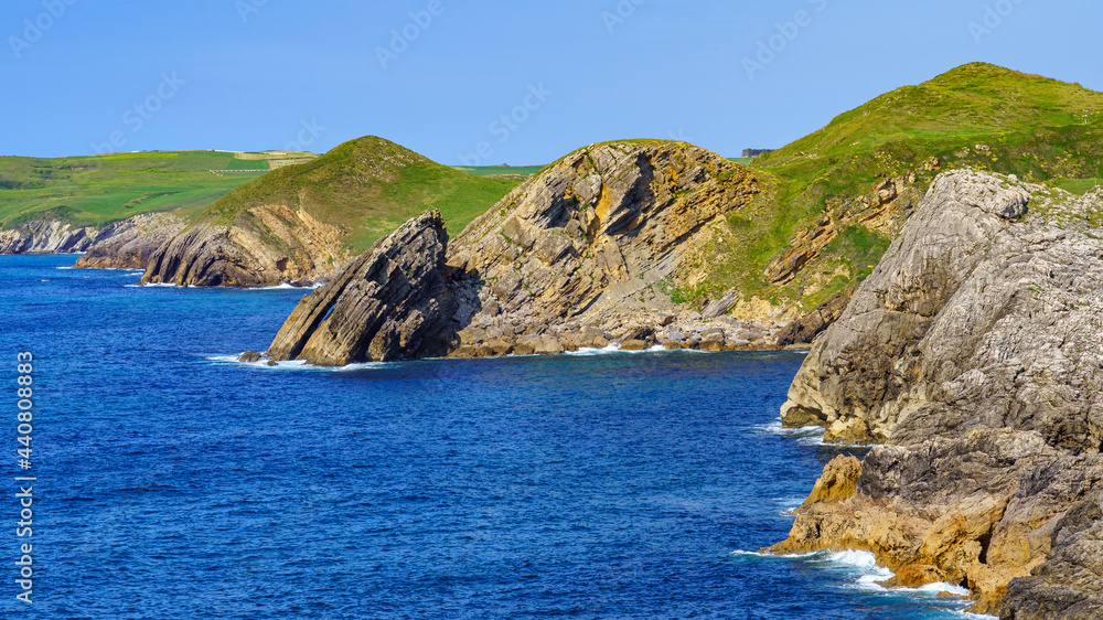 Fototapeta premium Rock cliffs jutting into the blue sea in the Cantabrian Sea. Santander.