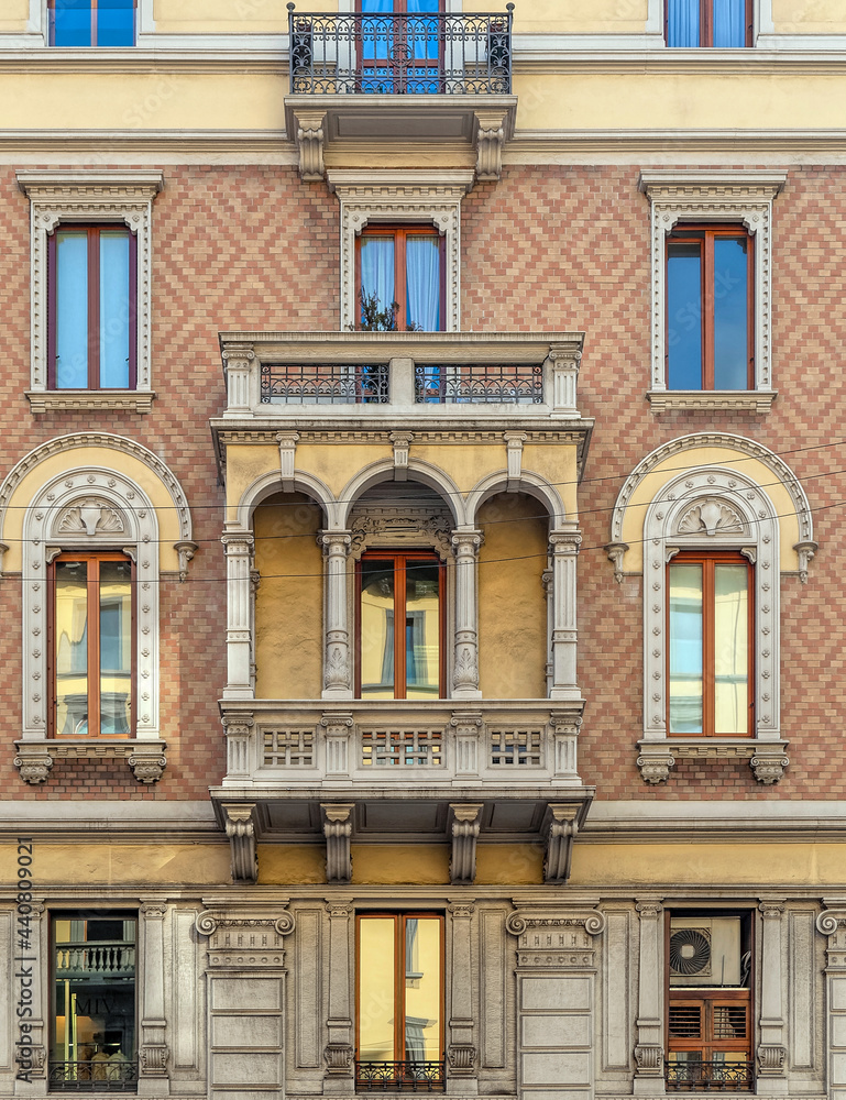Milan Italy, vintage house decorated front facade with balconies and windows