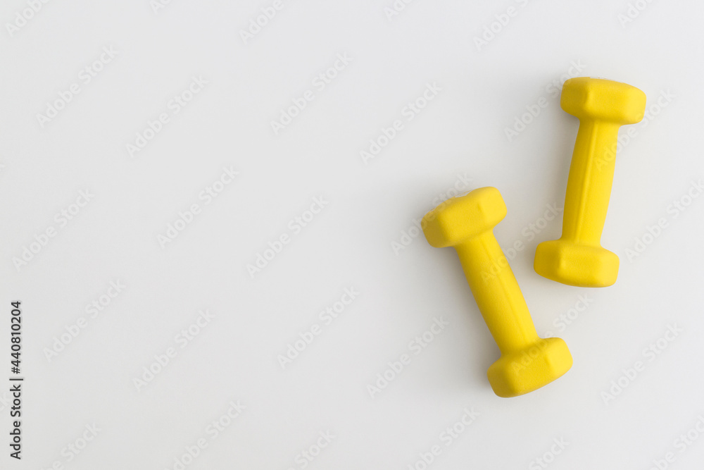 Pair of yellow dumbbells on white background Pair of yellow dumbbells on white background