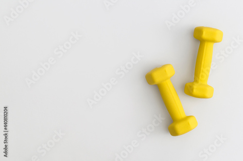 Pair of yellow dumbbells on white background