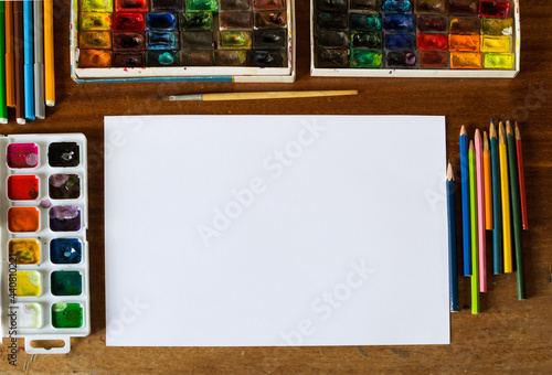 Artist's table with a sheet of paper and art tools, flat lay, selective focus